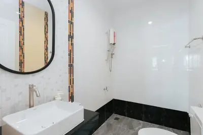 a white bathroom with a sink and a mirror at Baan Sutra Guesthouse in Phuket Town