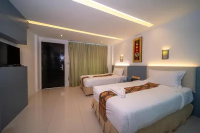 a hotel room with two beds and a television at Blue Carina Hotel Phuket in Phuket Town