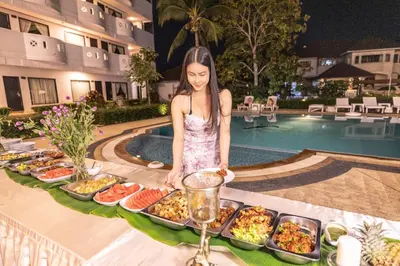 a girl standing next to a buffet of food by a pool at Blue Carina Hotel Phuket in Phuket Town