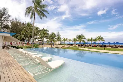 a swimming pool with lounge chairs and palm trees at Angsana Laguna Phuket in Bang Tao Beach