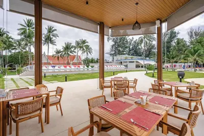 a restaurant with tables and chairs and palm trees at Angsana Laguna Phuket in Bang Tao Beach