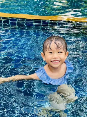 a young child is smiling in a swimming pool at Perennial Resort in Nai Yang Beach
