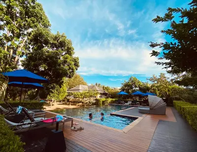 a pool with chairs and umbrellas on a wooden deck at Perennial Resort in Nai Yang Beach