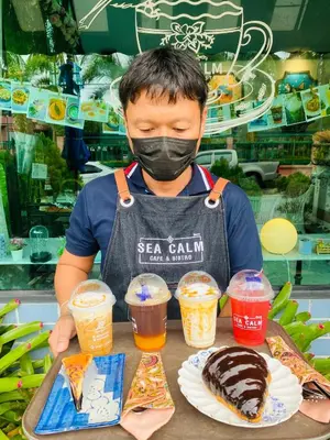 a man wearing a mask holding a table with drinks at Perennial Resort in Nai Yang Beach
