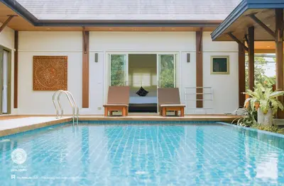 a swimming pool with two chairs and a house at One Bedroom Oriental Villa Nai Harn in Nai Harn Beach