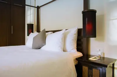 a bedroom with a bed with white pillows and a table at One Bedroom Oriental Villa Nai Harn in Nai Harn Beach