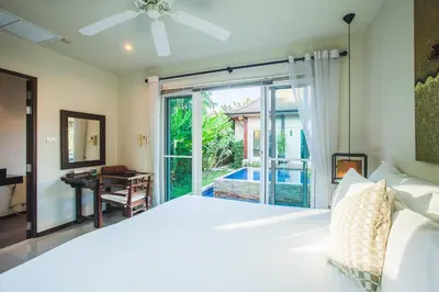 a bedroom with a bed and a sliding glass door at One Bedroom Oriental Villa Nai Harn in Nai Harn Beach