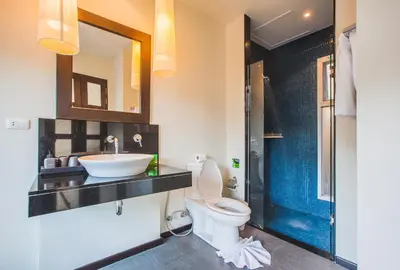 a bathroom with a toilet and a sink and a mirror at One Bedroom Oriental Villa Nai Harn in Nai Harn Beach