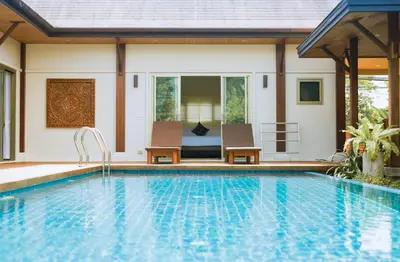 a swimming pool with two chairs and a house at Two Bedroom Oriental Villa Nai Harn in Nai Harn Beach