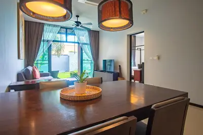 a dining room with a large wooden table with a plant on it at ONYX Villa Naiharn - 1 Bedroom with private pool in Nai Harn Beach