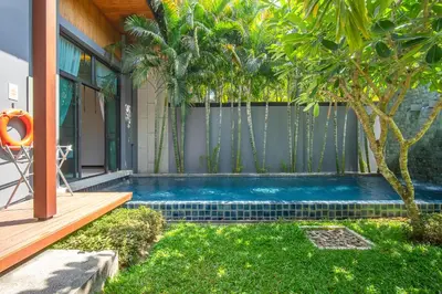 a swimming pool in front of a house with trees at ONYX Villa Naiharn - 1 Bedroom with private pool in Nai Harn Beach