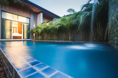 a swimming pool in front of a house with palm trees at ONYX Villa Naiharn - 2 Bedrooms with private pool in Nai Harn Beach
