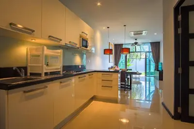 a kitchen with white cabinets and a sink and a table at ONYX Villa Naiharn - 2 Bedrooms with private pool in Nai Harn Beach