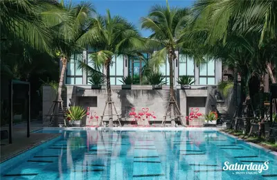 a swimming pool with palm trees in front of a building at Saturdays Residence - 1 Bedroom Service Apartment in Rawai Beach