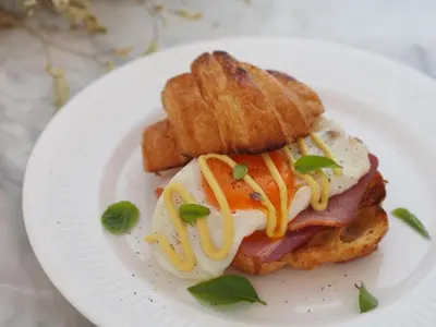 a white plate with a sandwich with eggs and toast at Saturdays Residence - 1 Bedroom Service Apartment in Rawai Beach
