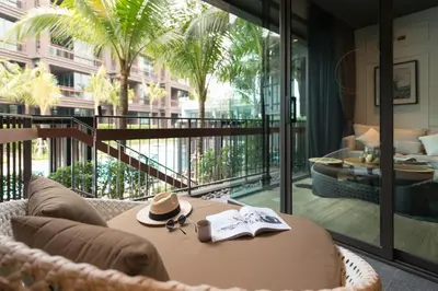 a table with a hat and a book on a balcony at Saturdays Residence - 2 Bedrooms Service Apartment in Rawai Beach