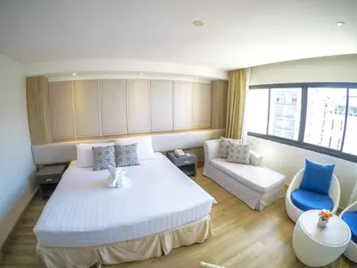a bedroom with a bed and a couch and a chair at Hiran Residence in Patong Beach
