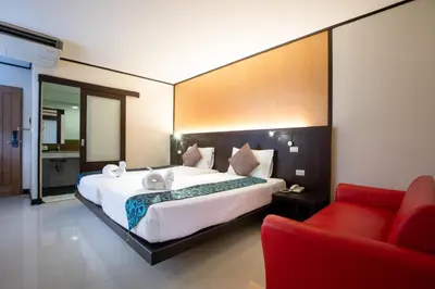 a bedroom with a large bed and a red couch at Orchid Garden Hotel Patong in Patong Beach