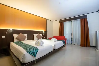 a bedroom with a large bed and a red chair at Orchid Garden Hotel Patong in Patong Beach