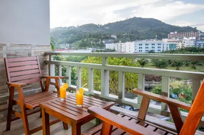 a balcony with a wooden table and chairs and a view at Orchid Garden Hotel Patong in Patong Beach