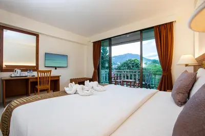 a bedroom with a bed and a desk and a window at Orchid Garden Hotel Patong in Patong Beach