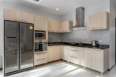 a kitchen with wooden cabinets and a stainless steel refrigerator at Trixie Town House 3 With Private Pool in Rawai Beach
