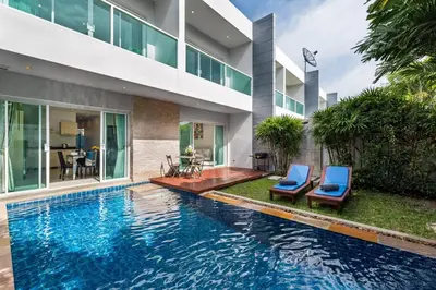 a swimming pool with two blue chairs next to a house at Trixie Town House 3 With Private Pool in Rawai Beach