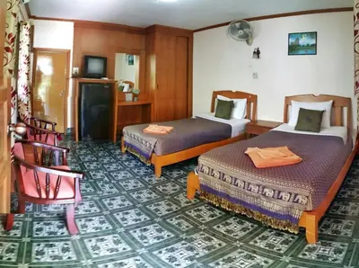 a hotel room with two beds and a chair at Anawin Bungalows in Ao Nang Beach