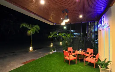 a patio at night with a table and chairs at Cool Residence Hotel in Phuket Town