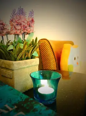 a candle on a table next to a pot of flowers at Cool Residence Hotel in Phuket Town