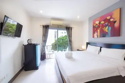a bedroom with a large white bed and a window at Baan Yuyen Karon Guesthouse in Karon Beach