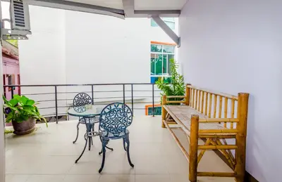 a balcony with a table and chairs and a bench at Baan Yuyen Karon Guesthouse in Karon Beach