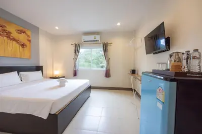 a bedroom with a bed and a television in a room at Baan Yuyen Karon Guesthouse in Karon Beach