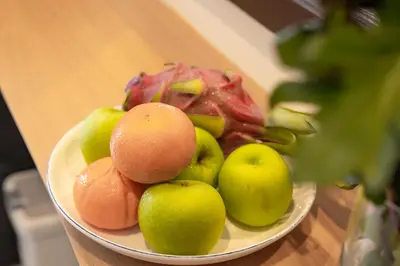 a plate of apples and oranges on a table at Baan Yuyen Karon Guesthouse in Karon Beach