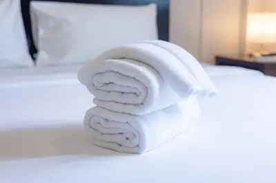 a stack of towels sitting on a bed at Baan Yuyen Karon Guesthouse in Karon Beach