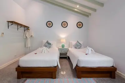 two beds in a white room with clocks on the wall at Kalim Beach House - Private Beach & Pool in Patong Beach