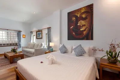 a bedroom with a large white bed and a living room at Kalim Beach House - Private Beach & Pool in Patong Beach