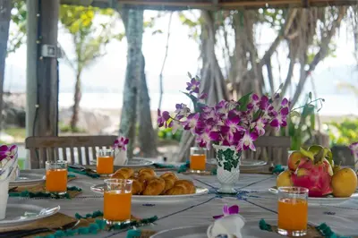 a table with plates of fruit and flowers on it at Kalim Beach House - Private Beach & Pool in Patong Beach