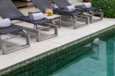 a row of lounge chairs next to a swimming pool at Kalim Beach House - Private Beach & Pool in Patong Beach