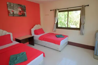 two beds in a room with red walls at Pineapple Guesthouse in Karon Beach