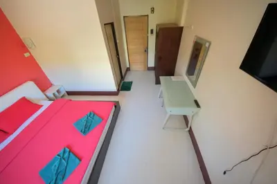 a room with a bed and a desk and a tv at Pineapple Guesthouse in Karon Beach