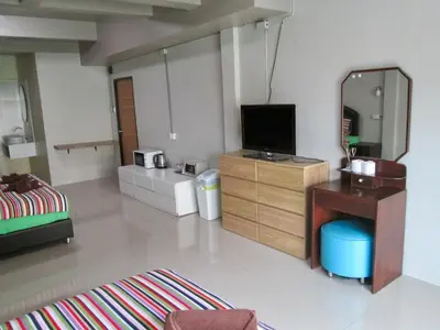 a living room with a television and a mirror at Pineapple Guesthouse in Karon Beach