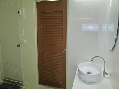 a bathroom with a toilet with a wooden door at Pineapple Guesthouse in Karon Beach