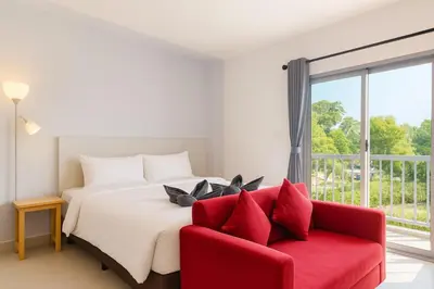 a bedroom with a bed and a red couch at Anattaya Holiday Home in Ko Yao Noi