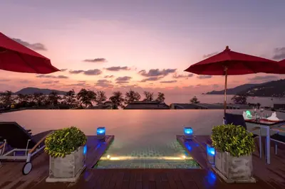 a swimming pool with a table and umbrellas at Luxury Beach Apartments by MVP in Patong Beach