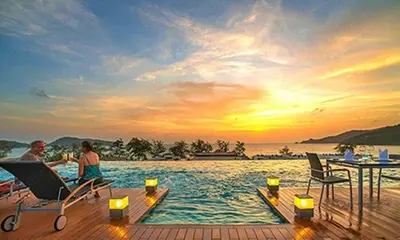 a man and a woman sitting on a deck in the water at Luxury Beach Apartments by MVP in Patong Beach