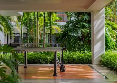 a bench in front of a building with trees at Naithonburi Beach Resort - SHA Extra Plus in Nai Thon Beach