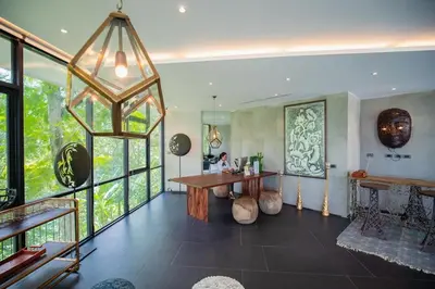 a living room with a table and some windows at The Woods Natural Park Resort Phuket in Kamala Beach