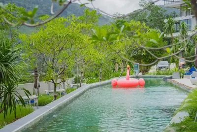 a swimming pool in a resort with a red float in the water at The Woods Natural Park Resort Phuket in Kamala Beach