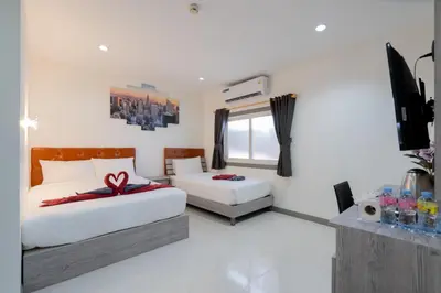 a bedroom with two beds and a flat screen tv at Square One Hotel Patong in Patong Beach